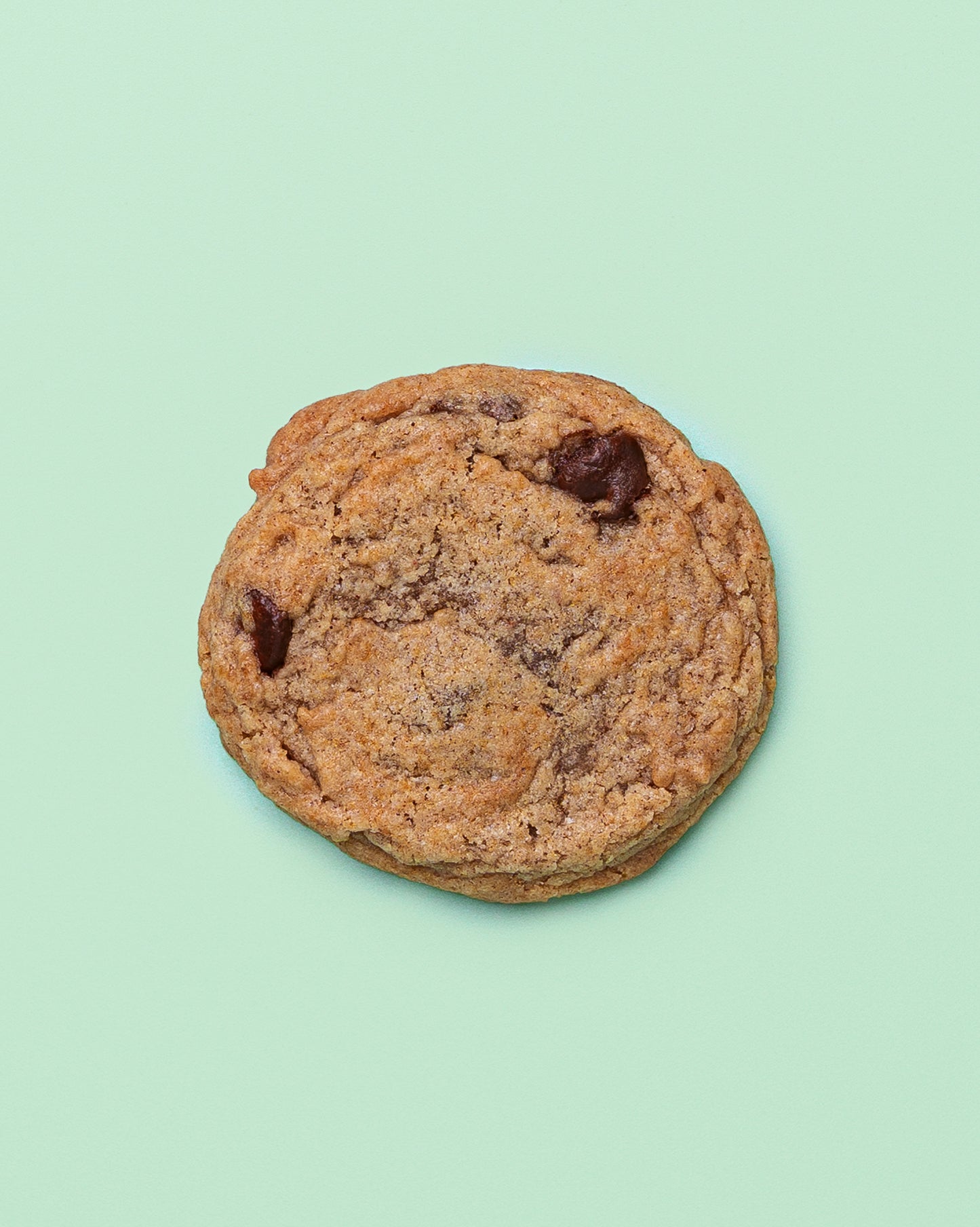 Close-up of a Banana Chocolate Chip Cookie with golden crispy edges, a soft chewy center, and melty chocolate chips throughout.