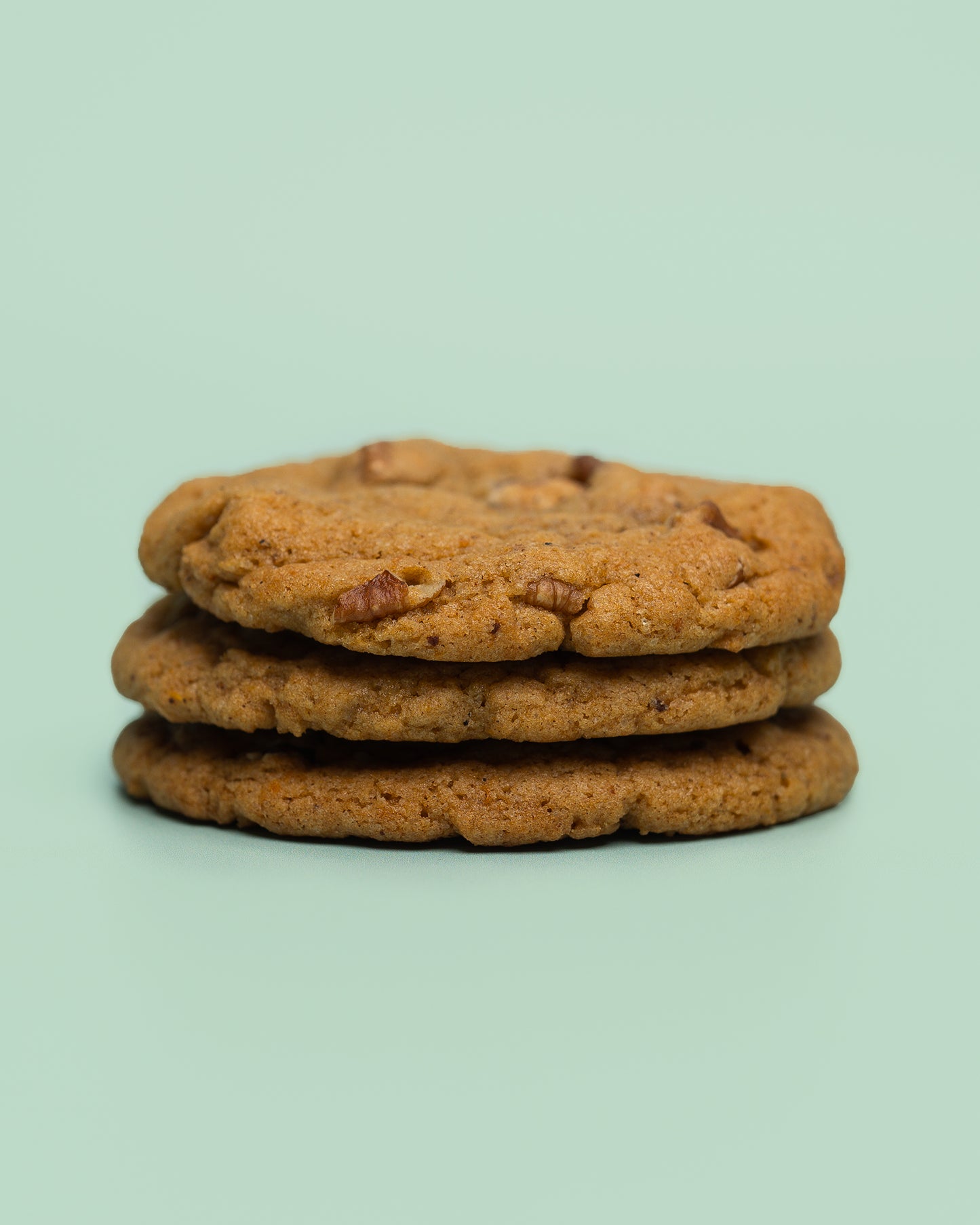 Close-up of the Pecan Sweet Potato Chai Cookie, showcasing its golden-brown exterior with hints of warm spices. The soft, chewy texture is packed with sweet potato, crunchy pecans, and aromatic chai flavors, creating the perfect balance of sweetness and spice. A decadent treat with cozy, fall-inspired flavors in every bite.