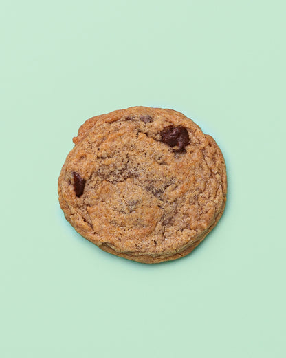 Close-up of a Banana Chocolate Chip Cookie with golden crispy edges, a soft chewy center, and melty chocolate chips throughout.