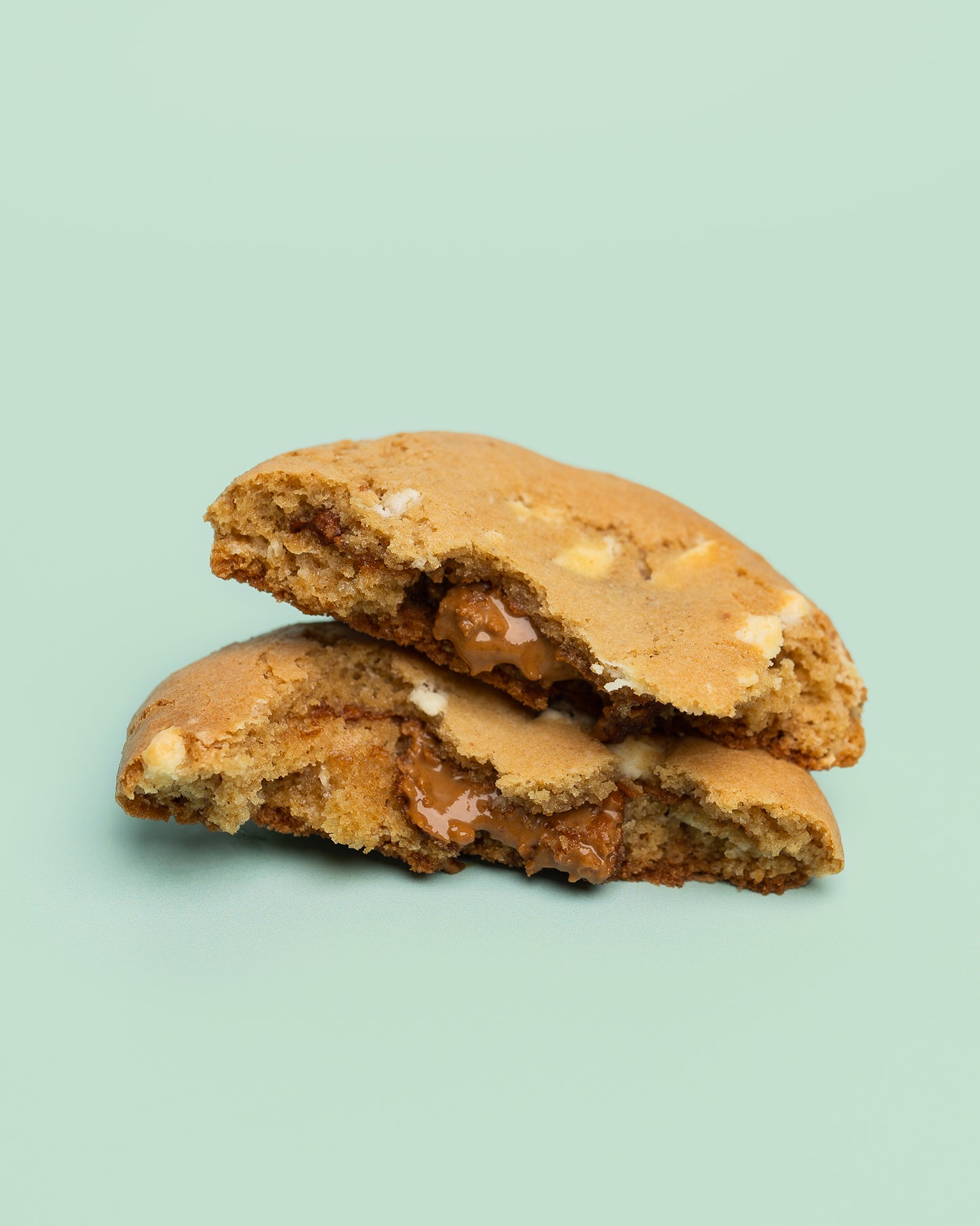 Close-up image of a Stuffed Biscoff Cookie with a golden-brown exterior, cracked top, and creamy Biscoff spread oozing from the center.