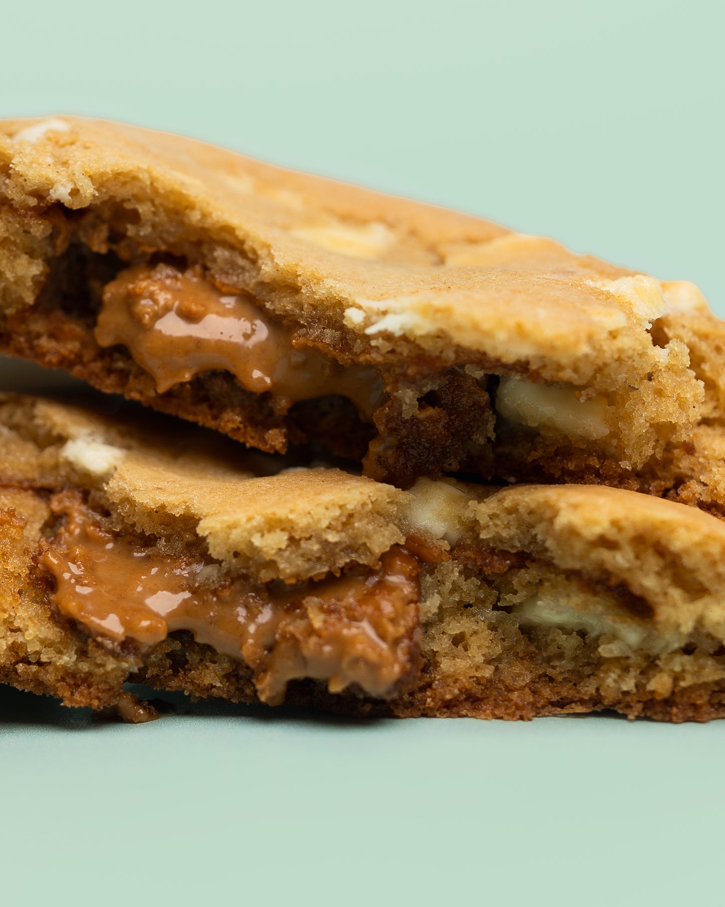 Close-up image of a Stuffed Biscoff Cookie with a golden-brown exterior, cracked top, and creamy Biscoff spread oozing from the center.